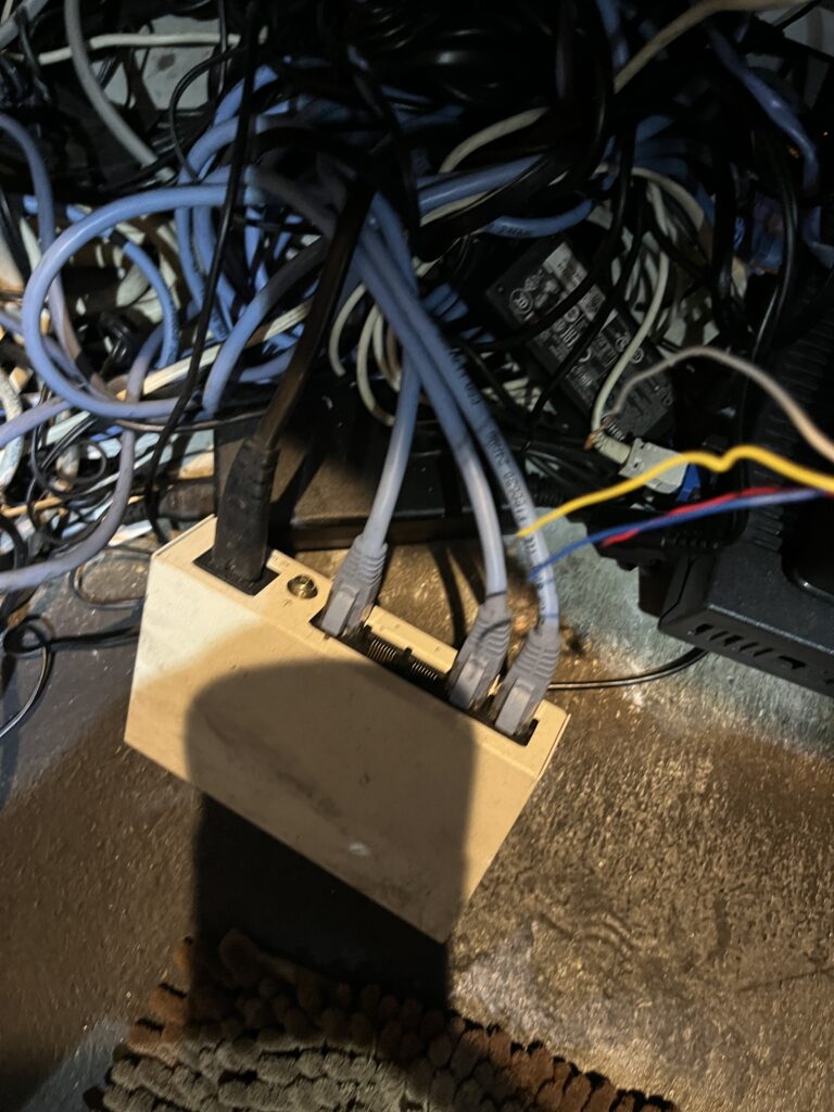 机の下で電源やLANケーブルが絡まっている整理前の状態